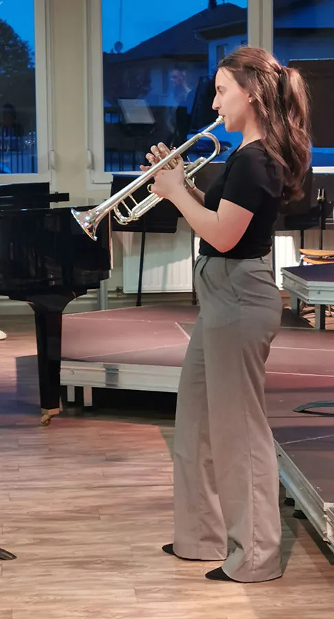 Jeune trompettiste debout jouant près du piano à queue aux auditions de printemps 2026 à Golbey