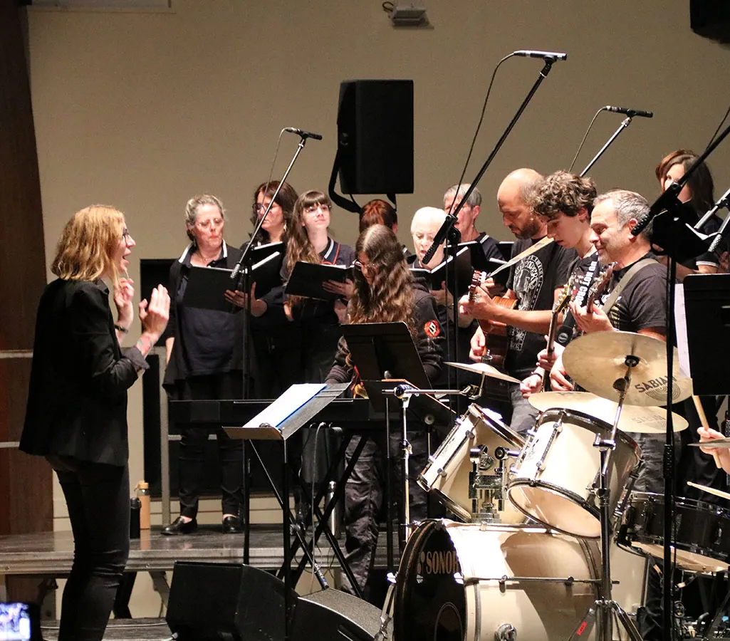 La cheffe de chœur devant les choristes avec piano, guitare et batterie — un festival de chant avec la chorale Coup de Chœur de Golbey, 25 mai 2025
