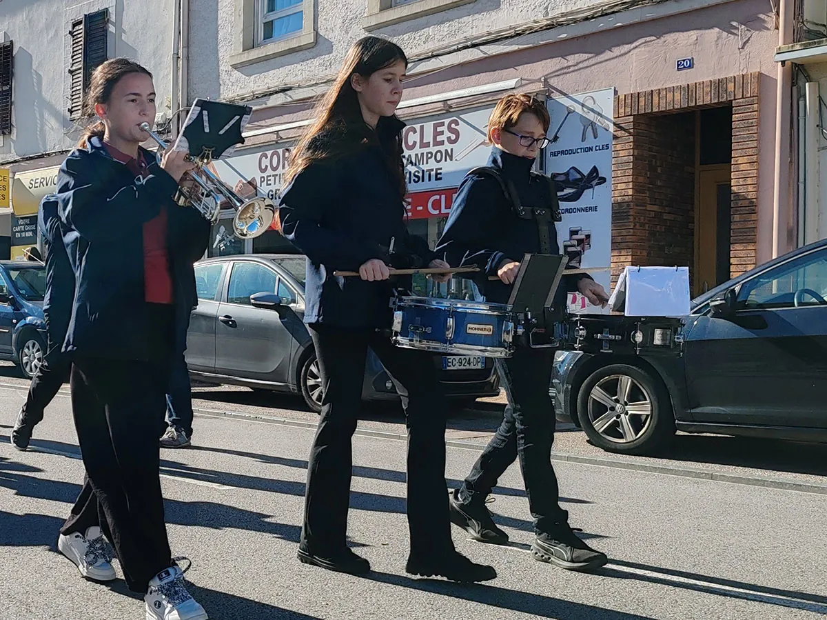 De jeunes musiciens de l’harmonie marchant et jouant en formation, vu de face — le défilé de la fête de Sainte-Fleur, 11 octobre 2025