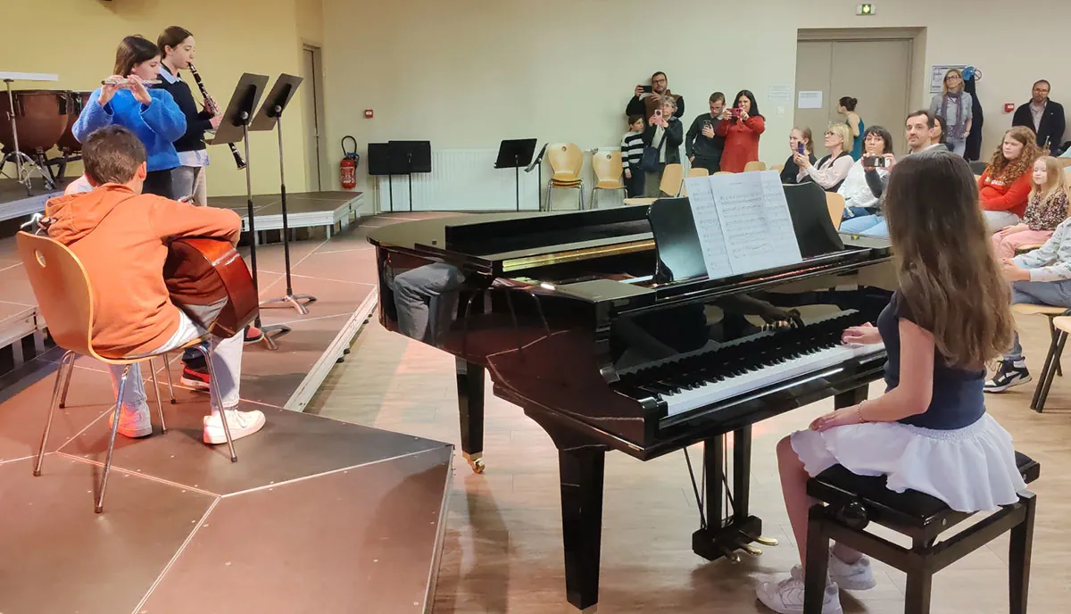 Un groupe d’adolescents en prestation avec piano, guitare et instruments à vent, vu de face — 10 avril 2026
