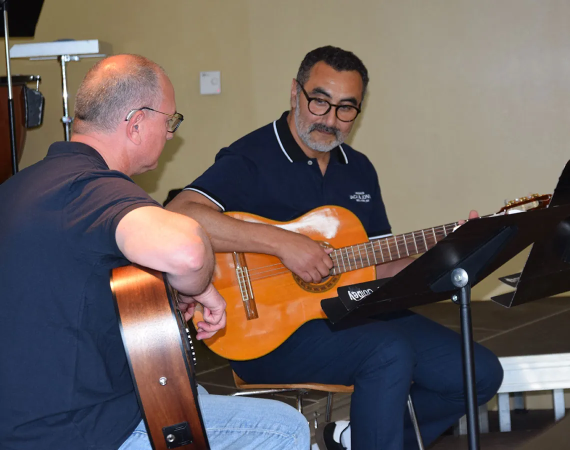 Deux guitaristes assis jouant ensemble, en plan rapproché — les auditions de juin 2024