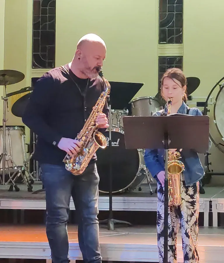 Un duo de saxophones réunissant un adulte et une jeune musicienne derrière un pupitre — les auditions de décembre 2024
