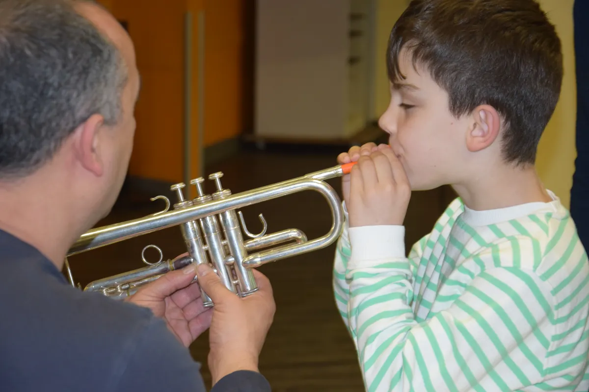 Professeur accompagnant un jeune garçon qui essaie la trompette