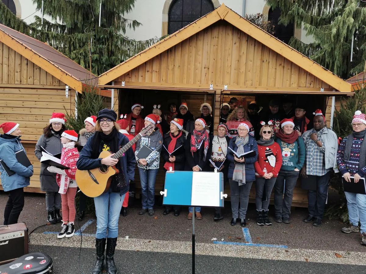 Chorale de Golbey chantant en plein air avec une guitariste pendant les fêtes de Noël