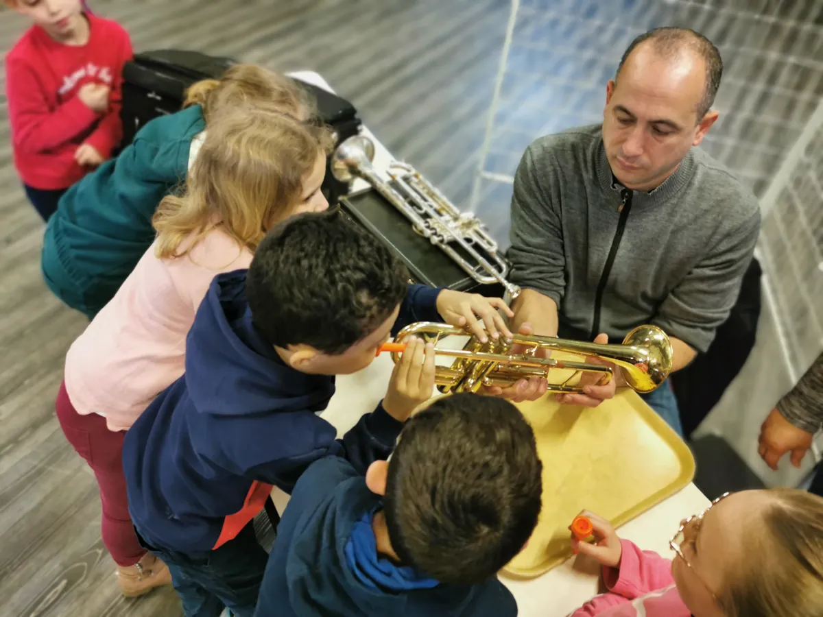 Professeur faisant essayer une trompette à plusieurs enfants