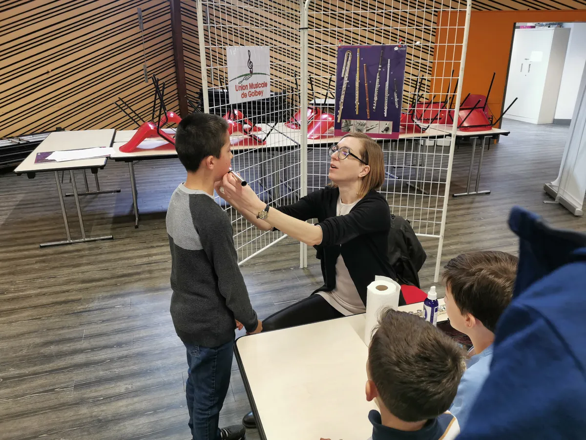 Professeure de flûte expliquant l’embouchure à un jeune garçon