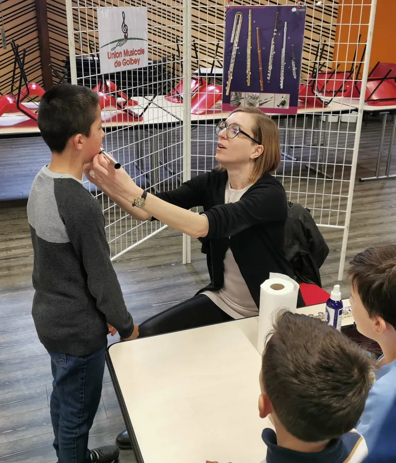 Julie Aubert guidant un jeune élève sur le placement de l'embouchure de flûte