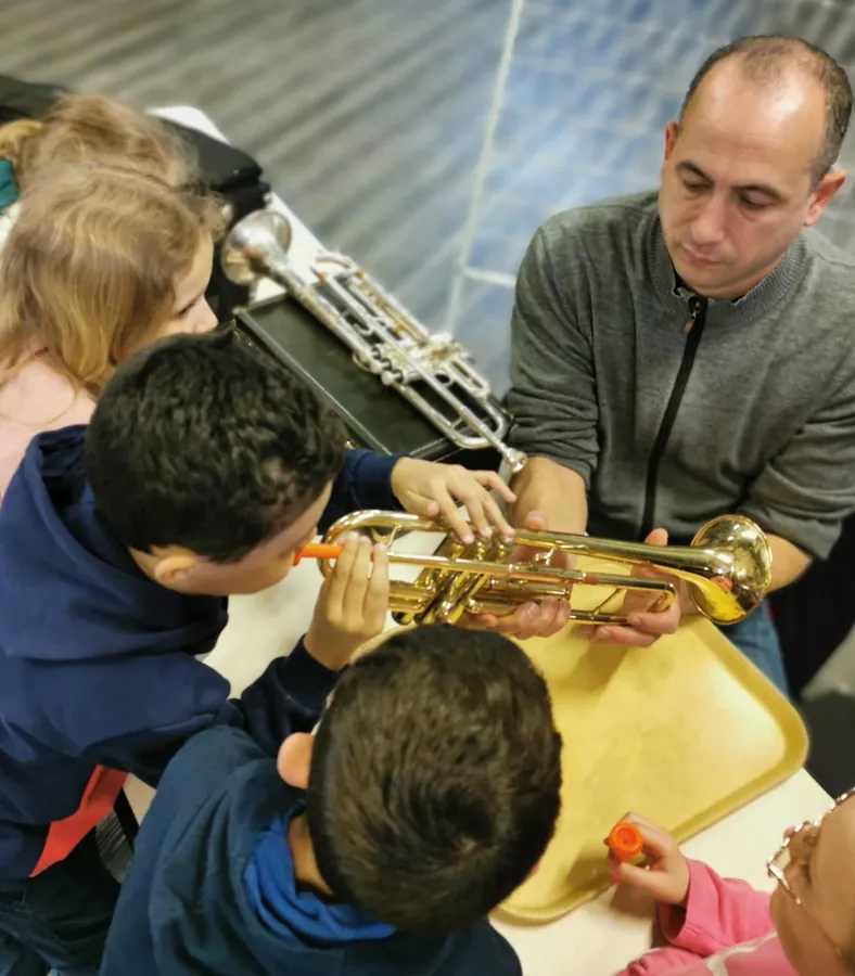 Loïc Sonrel faisant découvrir la trompette à un groupe de jeunes enfants
