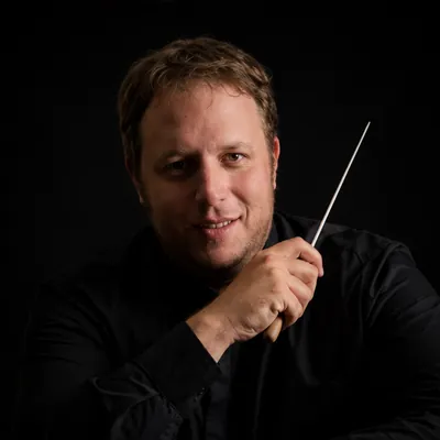 Portrait d'Arnaud George, chef d'orchestre, tenant une baguette de direction